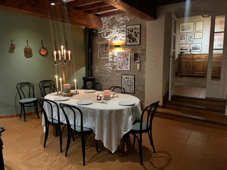 Dezelfde keuken, de tafel in het wit gedekt met brandende kaarsen.